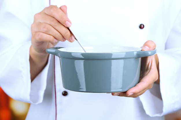 Ręka trzymająca łyżkę nad garnkiem